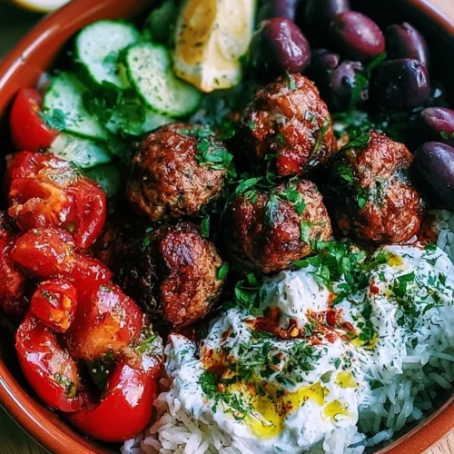 A flavorful Greek meatball bowl topped with fresh herbs and vegetables